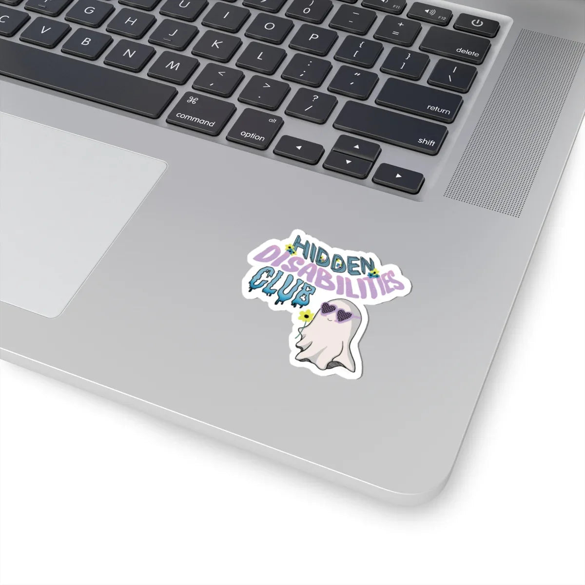 Durable, long-lasting sticker on a skateboard with text "Hidden Disabilities Club" in colorful pastel, playful font, and a smiling ghost wearing sunglasses, holding a yellow flower. Fun and inclusive tone.