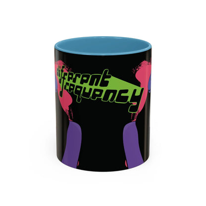 Side of mug with a glossy black exterior and glossy blue interior, and the phrase "different frequency" in bold, stylized neon green and black text. 