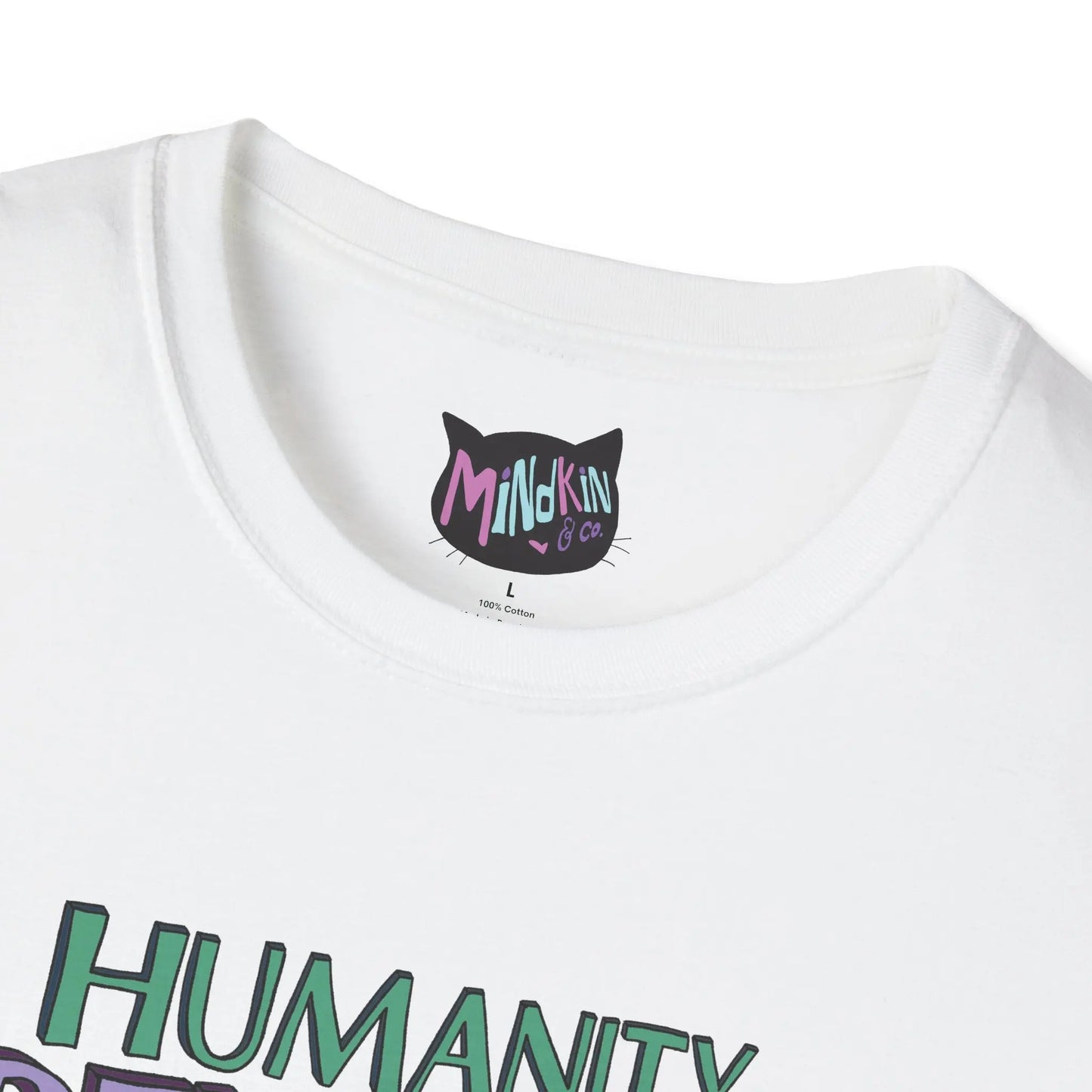 Close-up of a white T-shirt featuring colorful "Mindkin & Co." branding on the tag. The word "HUMANITY" is partially visible in vibrant green below.