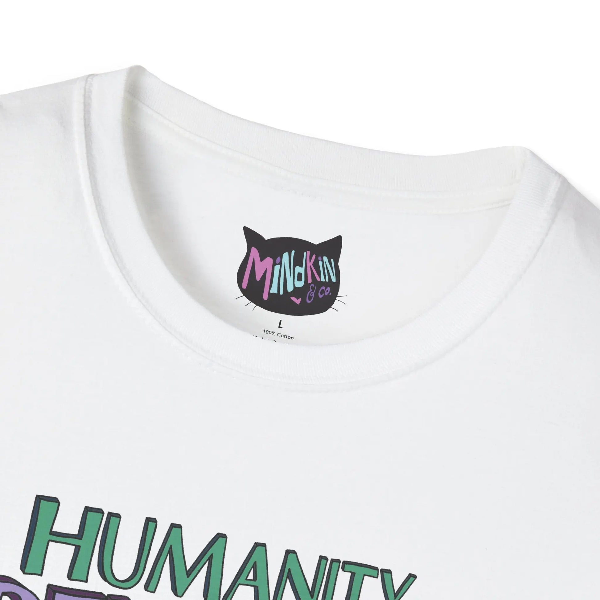 Close-up of a white T-shirt featuring colorful "Mindkin & Co." branding on the tag. The word "HUMANITY" is partially visible in vibrant green below.