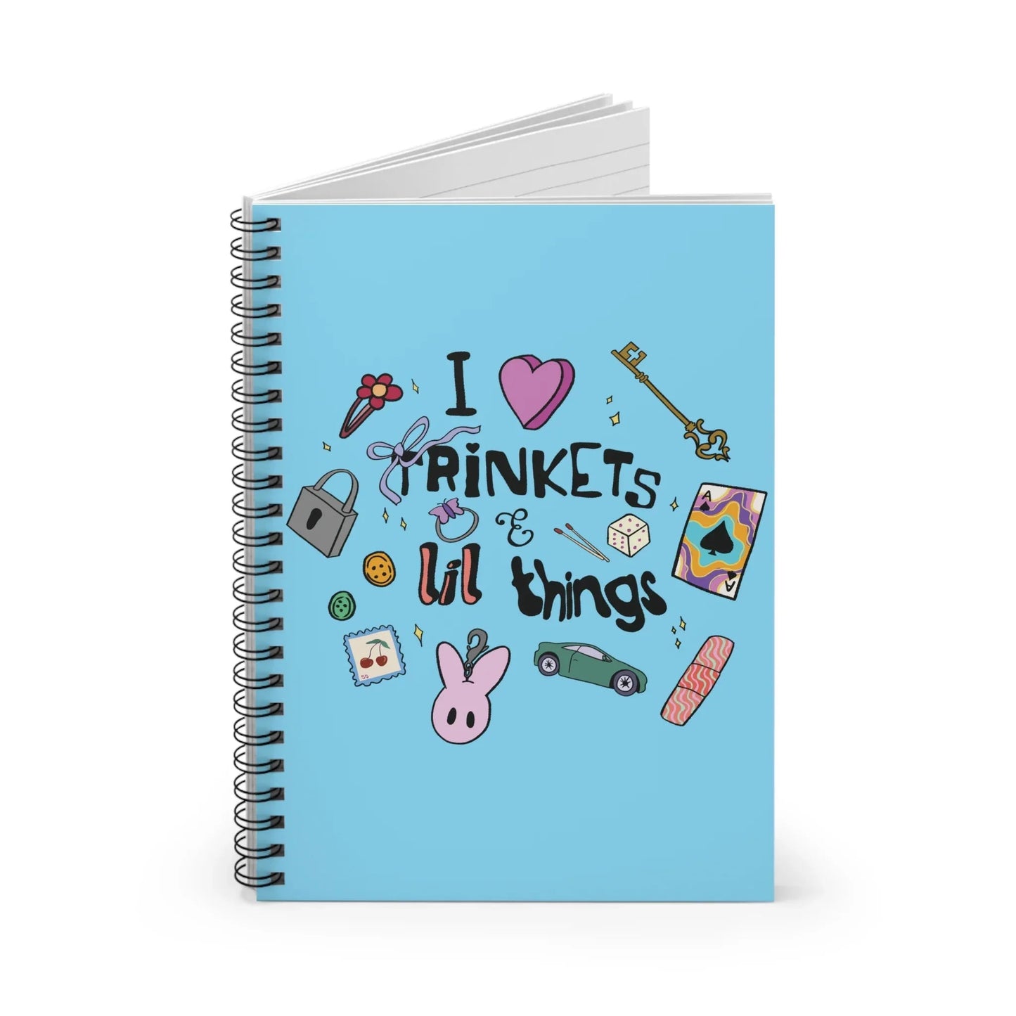 Light blue spiral notebook cover with doodles, including a key, lock, dice, and toy car. Text reads "I love trinkets & lil things" with playful imagery.