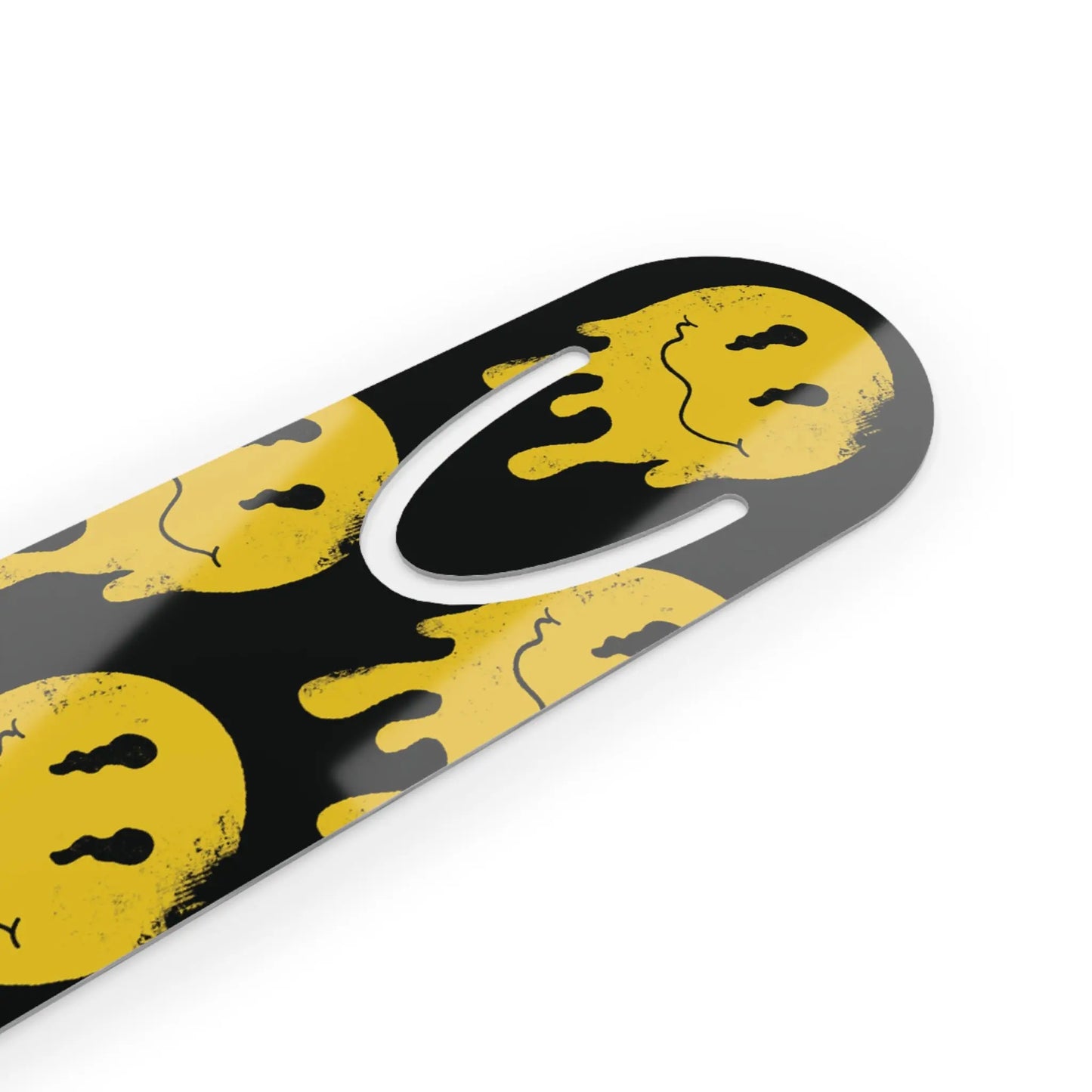 Close-up of a black bookmark with a white inner cutout, featuring yellow, irregularly shaped smiley faces with distorted features, creating a quirky, edgy tone.