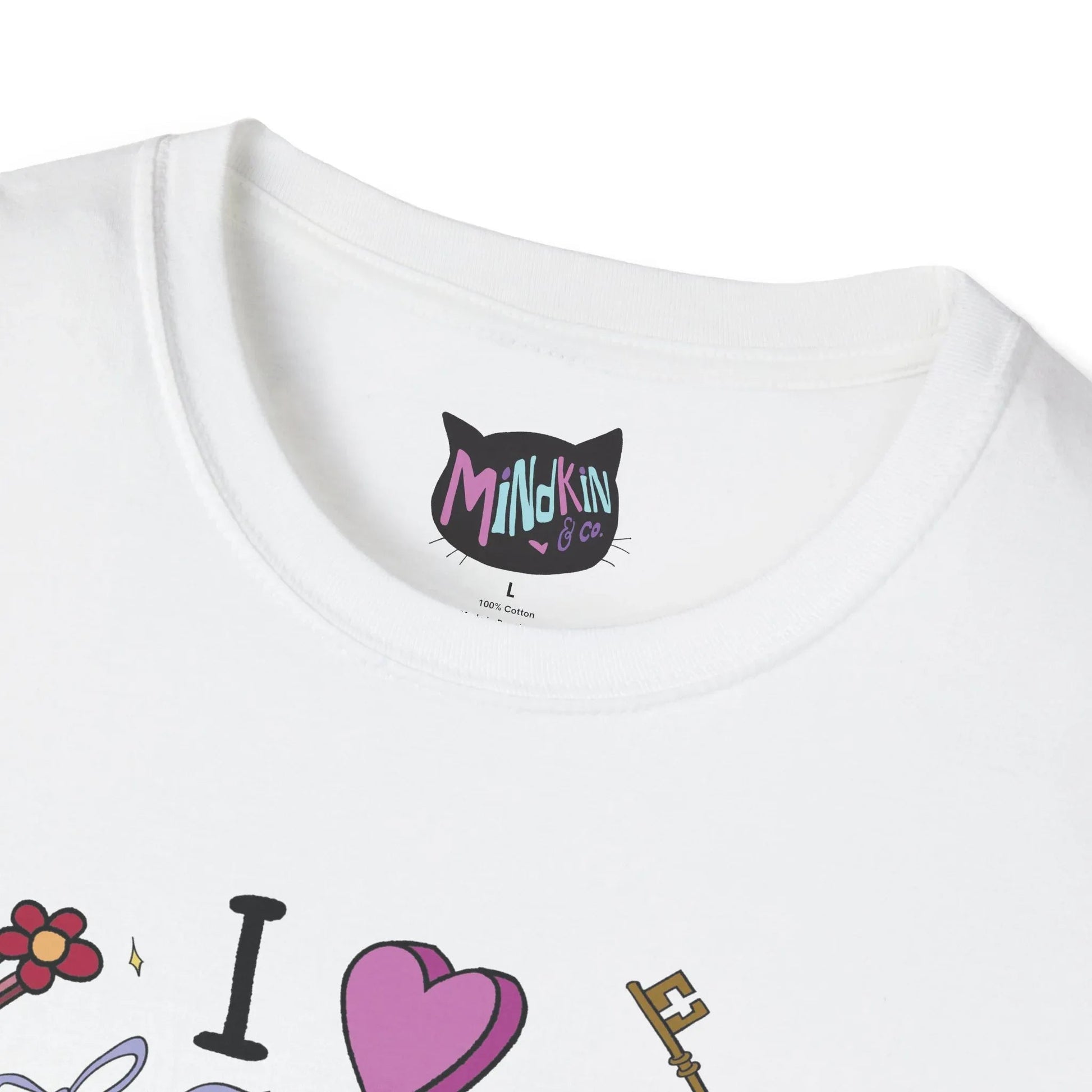 Close-up of a white t-shirt's ribbed collar neckline showing a black cat-shaped label with "Mindkin & Co" in colorful text. Below are playful illustrations of a flower hairclip, "I ♥️" and a key.