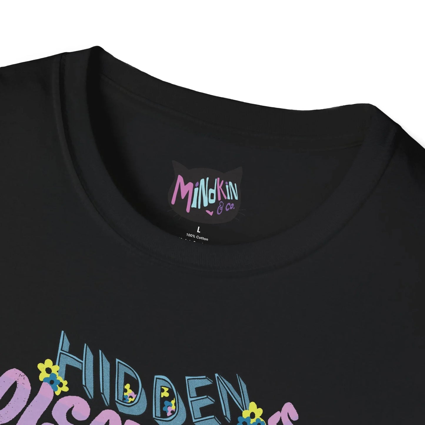 Close-up of a black T-shirt with ribbed collar and "Mindkin & Co." label in colorful letters. Below, partial view of "Hidden" text with small, colorful flowers.