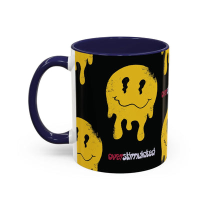 Black mug with a yellow melting smiley face pattern, evoking a playful, edgy vibe. The word "overstimulated" appears in red and white text, with glossy navy handle and interior.