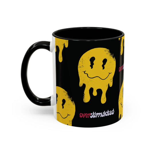 Black mug with a yellow melting smiley face pattern, evoking a playful, edgy vibe. The word "overstimulated" appears in red and white text.